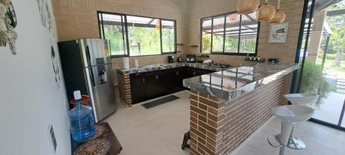 a large kitchen with a refrigerator and a counter at Villa Jana Casa campestre cerca a Villeta in Quebradanegra