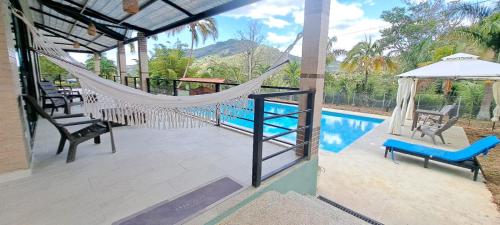 a hammock on a porch next to a swimming pool at Villa Jana Casa campestre cerca a Villeta in Quebradanegra