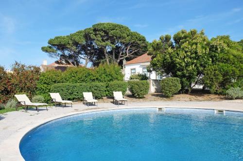 a swimming pool with chairs and a house at ST Pool Gardens SESIMBRA,Tranquility Beach 10min in Sesimbra
