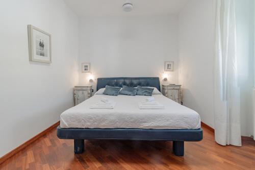 a bed in a room with white walls and wood floors at H11 MAISON BLEU Centro - Ariston in Sanremo