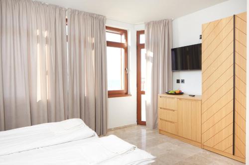 a bedroom with a bed and a cabinet and a window at Семеен хотел НОА in Nesebar