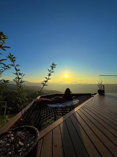 a woman laying on a deck watching the sunset at Sítio Recanto Azul in Barracão
