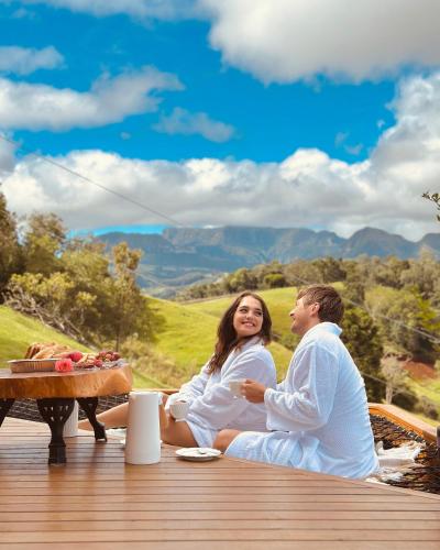 a man and woman sitting on a deck with a table at Sítio Recanto Azul in Barracão