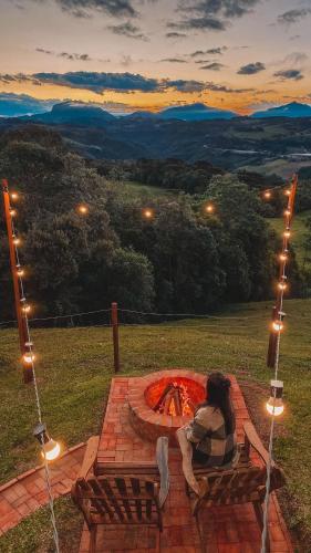 a woman sitting on a bench next to a fire pit at Sítio Recanto Azul in Barracão