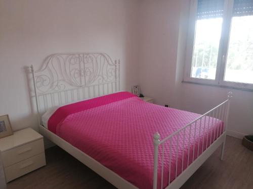 a white bedroom with a bed with a pink comforter at Casa Vacanze Brezza Marina with beautiful garden in Quartu SantʼElena