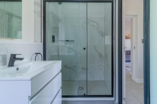a bathroom with a glass shower and a sink at #AlimamaSpaces Pano's Munyaka in Vosburg