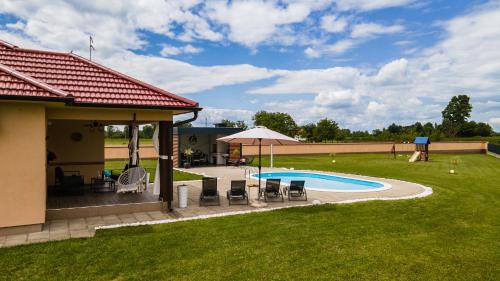 a backyard with a pool with chairs and an umbrella at Holiday House Drava Relax in Pitomača