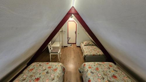 a attic room with two beds and a window at Vakantiehuis "It koaihûs" in Jistrum