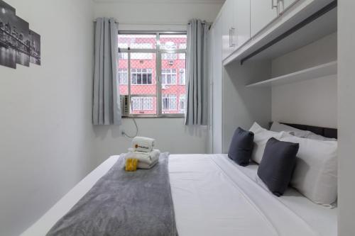 a bedroom with a white bed with a teddy bear sitting on it at Conforto a 6min da praia de Copacabana - BR801 in Rio de Janeiro