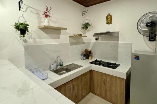 a white kitchen with a sink and a refrigerator at Villa Licia - Seseh area in Balian