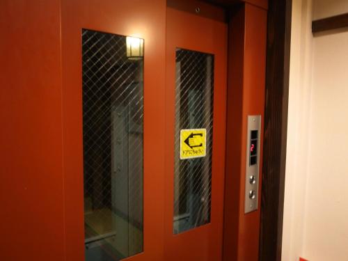 an orange elevator door with a sign on it at Ryokan Murayama in Takayama