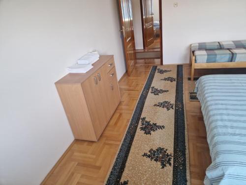 a bedroom with a dresser and a bed and a rug at Apartman Vujovic in Zlatište