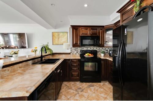 a kitchen with wooden cabinets and a black refrigerator at Entire Cozy Apartment with Share Jacuzzi to Enjoy Amazing Views in Halifax