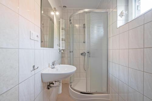 une salle de bain blanche avec lavabo et douche dans l'établissement Apartament Nostalgia, à Gąski