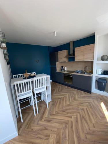 a kitchen with blue walls and a wooden floor at Welc'home in Saint-Valéry-en-Caux
