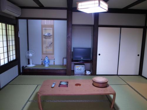 a living room with a table and a tv at Ryokan Murayama in Takayama