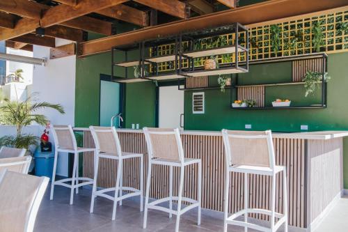 a bar with white chairs and a green wall at Fancy Oceanviews Condo In The Heart Of Playa Bonita in Las Terrenas