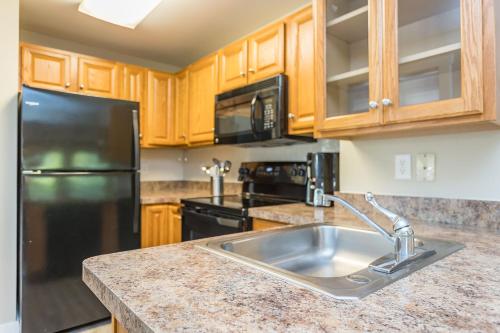 a kitchen with a sink and a black refrigerator at Massanuttens Shenandoah Villas by TripForth in McGaheysville