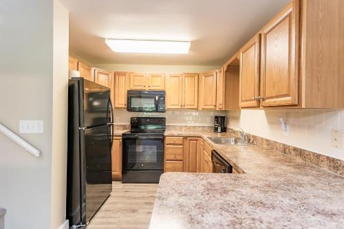 a kitchen with wooden cabinets and black appliances at Massanuttens Shenandoah Villas by TripForth in McGaheysville