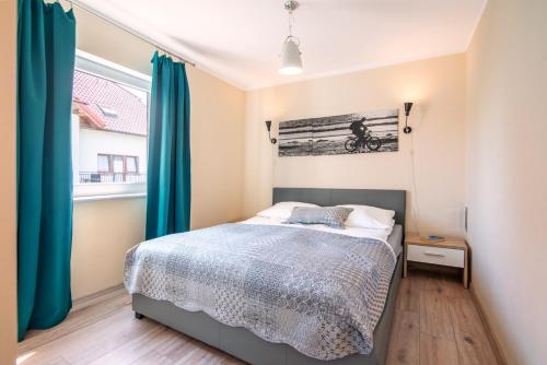 a bedroom with a bed with blue curtains at Nemo - apartament, domek w Gaskach in Gąski