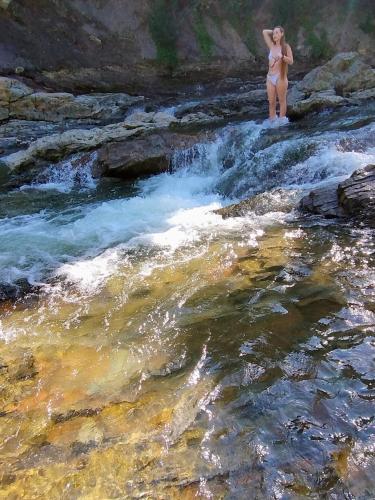 a woman in a bikini standing next to a river at Villa Medova in Kosiv