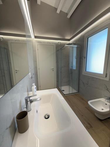a white bathroom with a sink and a shower at Omai suite in Ortona