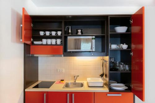 a small kitchen with red cabinets and a sink at Dvosobni komfort apartma GARBIN 711 Portoroz - Two Bedroom Comfort Apartment GARBIN 711 Portoroz in Portorož