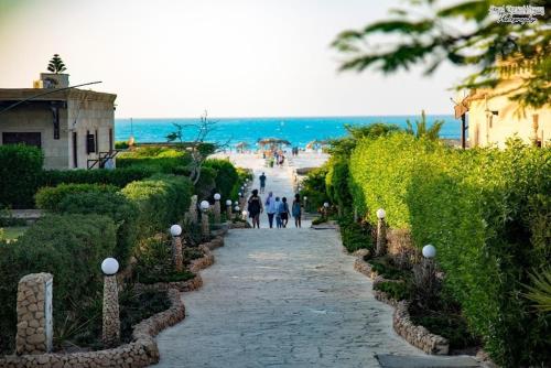 Dawwār Abū MaḩrūsにあるChalet with garden -sea view cleopatra village - kilo 86 - north coastのビーチ近くの石畳の道を歩く人々
