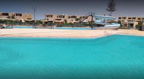 Dawwār Abū MaḩrūsにあるChalet with garden -sea view cleopatra village - kilo 86 - north coastの- リゾート内の青い水の大型スイミングプール