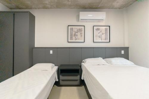 マリンガにあるEstilo e Praticidade no Centro - CA1505の壁に2枚の写真が飾られた客室で、ツインベッド2台が備わります。