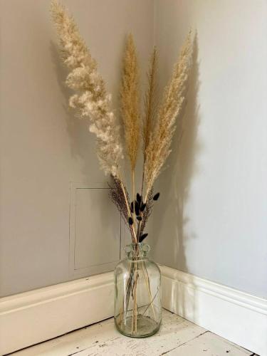 a glass vase with some dried flowers in it at Central 2br I Pets I Parking in Hereford