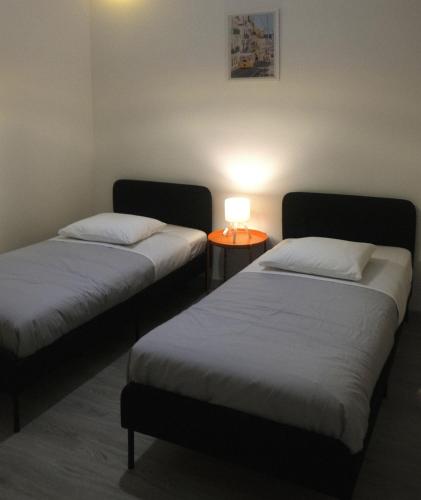 a room with two beds and a table with a lamp at Casa dos Pardais in Lisbon