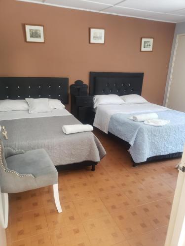 a room with two beds and a chair in it at Casa hotel la 33 in Medellín