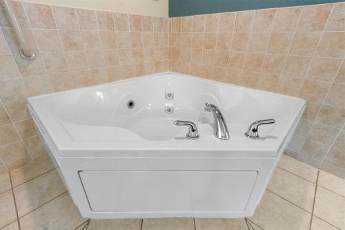 a white bath tub with two faucets in a bathroom at AmericInn by Wyndham Green Bay East in Green Bay