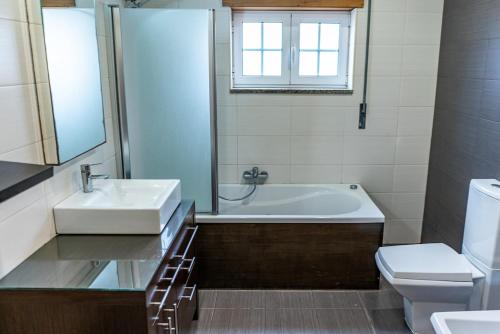 een badkamer met een bad, een wastafel en een toilet bij Beachfront Costa Nova Villa - 2BR Apartment in Gafanha da Encarnação