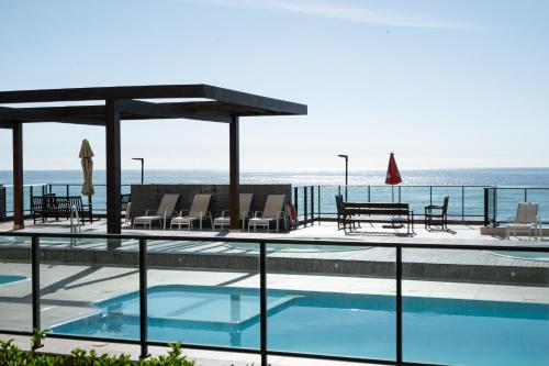 a swimming pool with a view of the ocean at Apto completo com VISTA MAR em CONDOMINIO RESORT FRENTE MAR em Barra Velha 2 quartos AR CONDICIONADO CHURRASQUEIRA privativa Cozinha Completa PISCINA vaga de Garagem - VIL3 in Barra Velha