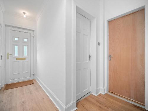 an empty hallway with a white door and wooden floors at Mollison 2 Bedroom Apartment - Harthill in Harthill