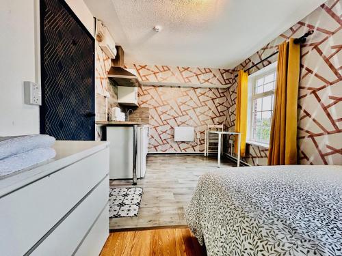 a bedroom with a bed and a kitchen with a window at Rest Boutique Wembley in London