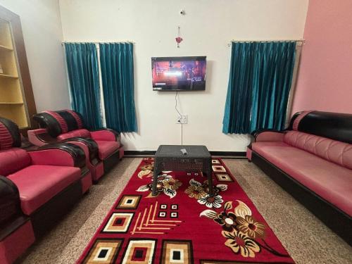 a room with two couches and a table with flowers on it at Formula1 Homestay in Mysore