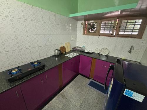 a kitchen with purple cabinets and a counter top at Formula1 Homestay in Mysore