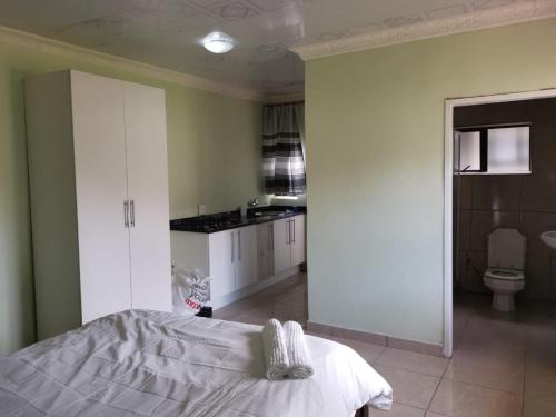 a bedroom with a bed and a bathroom with a toilet at Mahlambandlopfu Presidential Guest House in Vosburg