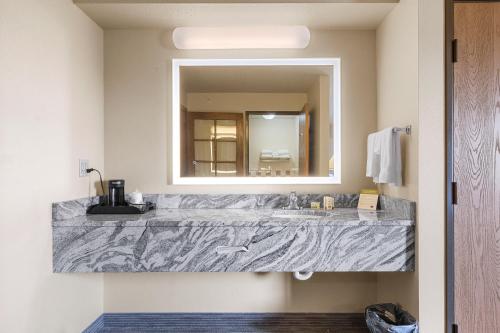 a bathroom with a large marble sink and a mirror at AmericInn by Wyndham Green Bay East in Green Bay