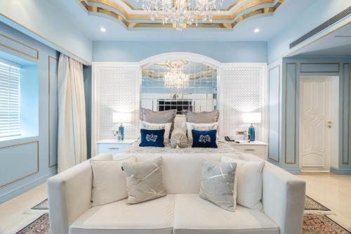 a bedroom with a white couch in front of a bed at The Claridges New Delhi in New Delhi
