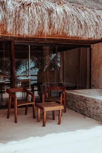 a group of chairs and a table and a straw roof at Niken Beachfront Tulum Hotel in Tulum