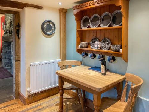 a dining room with a table and chairs and a clock at Marl Farm Cottage in Hayfield