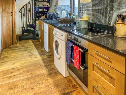 a kitchen with a washer and dryer under a counter at Marl Farm Cottage in Hayfield