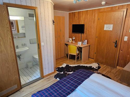a bedroom with a bed and a bathroom with a sink at Alpina Boutique Hotel Interlaken - Ringgenberg - Adults only ! in Ringgenberg