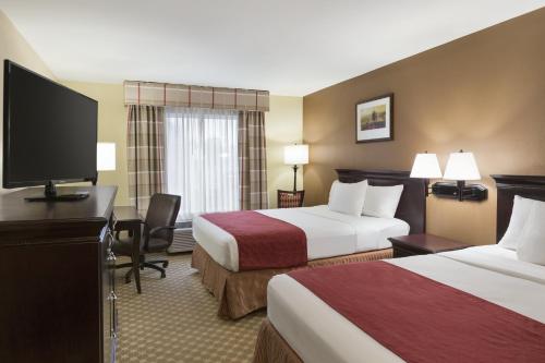 a hotel room with two beds and a flat screen tv at Country Inn & Suites by Radisson, Asheville - Outlet Mall in Asheville