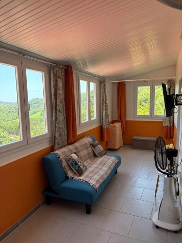 a living room with a blue couch and windows at Lumière Mandarine Martinique, Marin in Le Marin