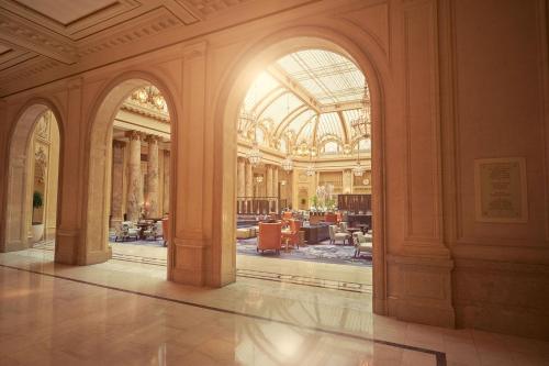 a large building with a lobby with columns and a room with tables at Palace Hotel, a Luxury Collection Hotel, San Francisco in San Francisco